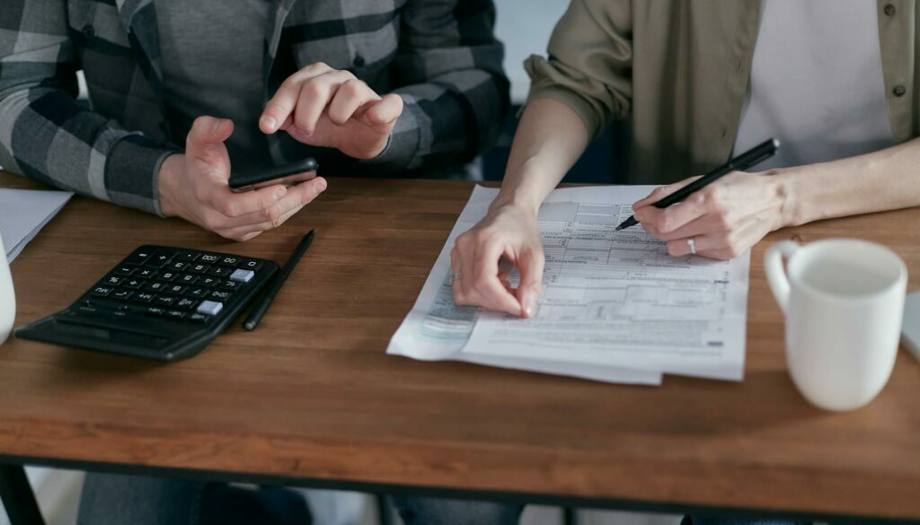 two people doing paperwork and computing taxes