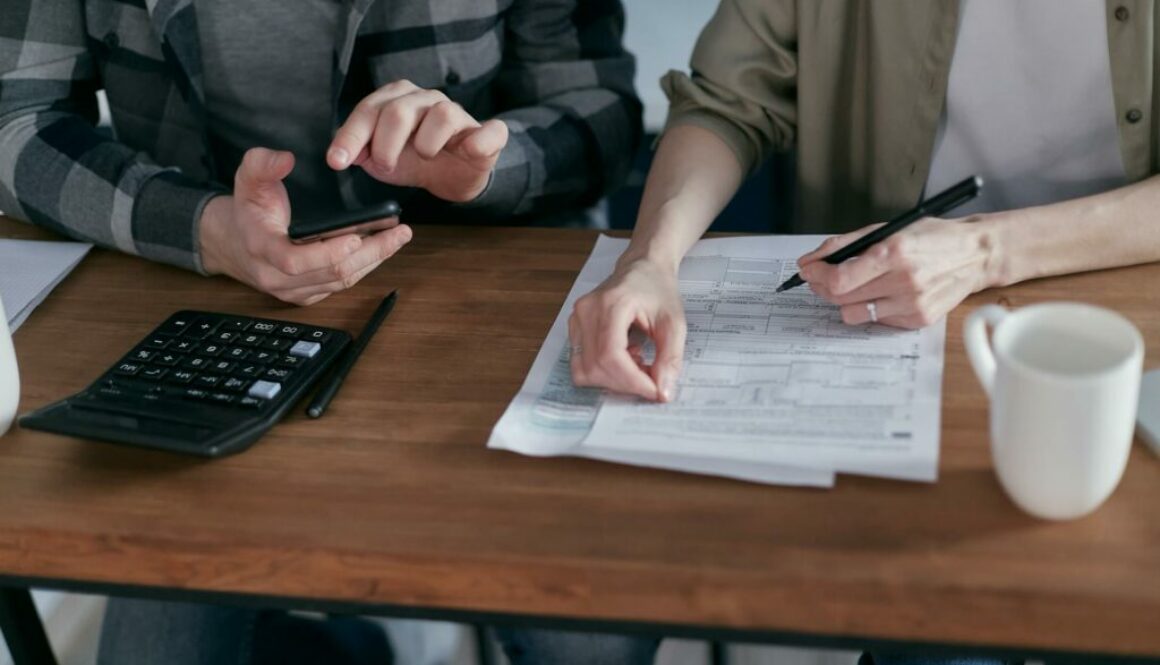 two people doing paperwork and computing taxes