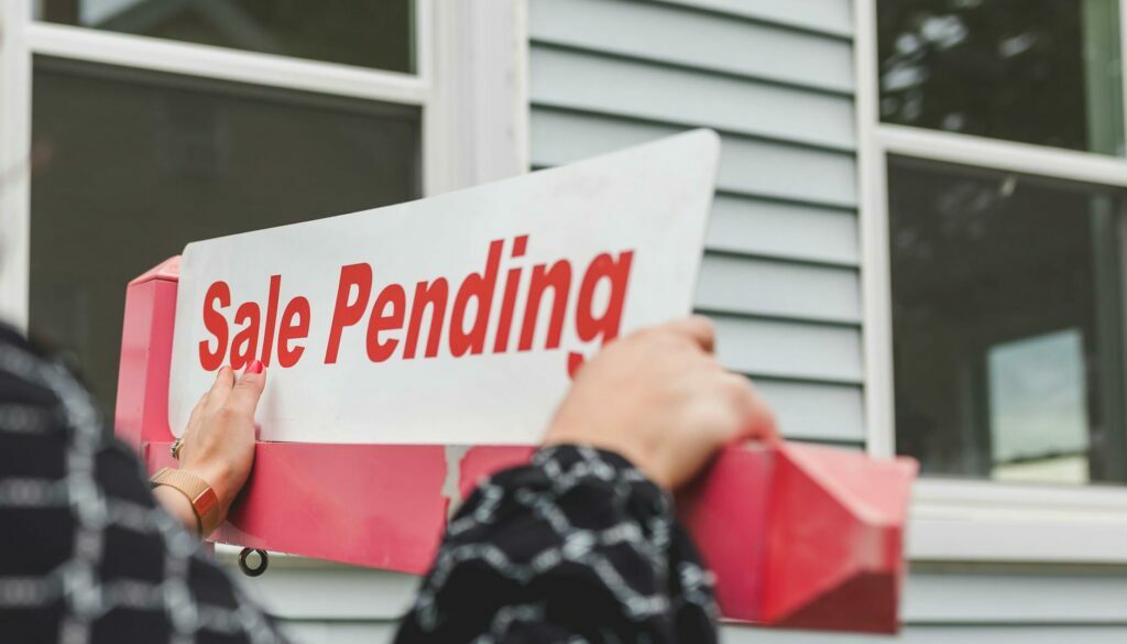 person holding a signage outside a house