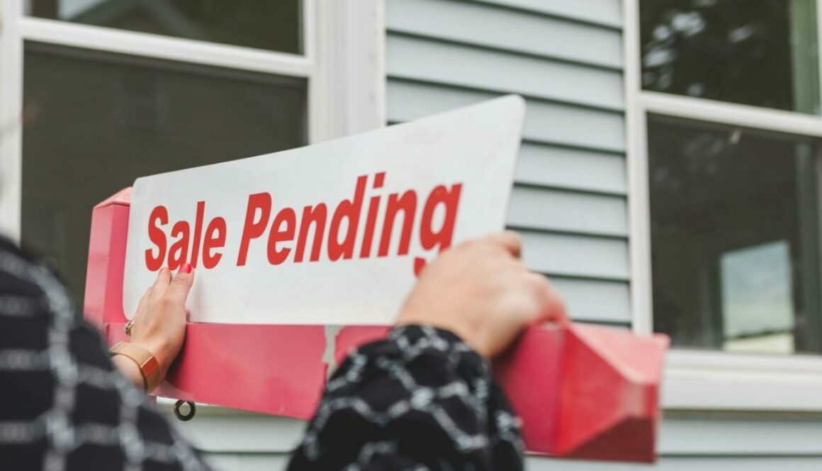 person holding a signage outside a house