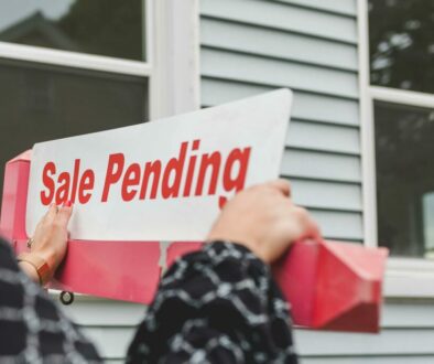 person holding a signage outside a house